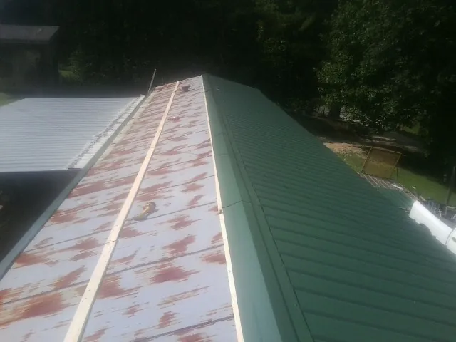 Old rusted panels beside newly installed green metal roofing — Wind Damage Roof Repair by Roofing Brothers in Jarrettsville