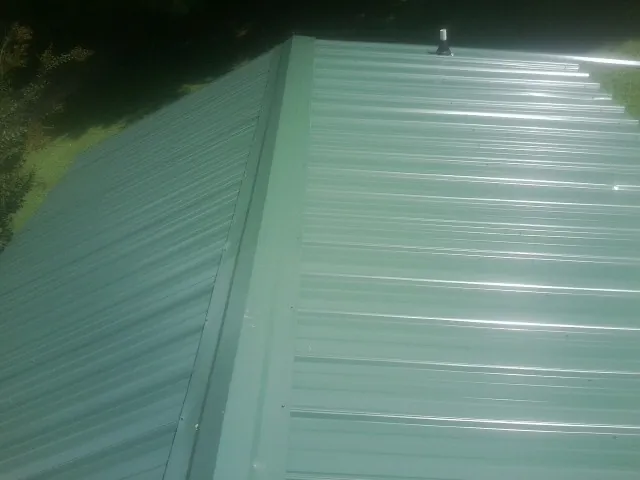 New green metal panels meeting at the ridge of a roof — Flat Roof Repair work by our crew in Jarrettsville