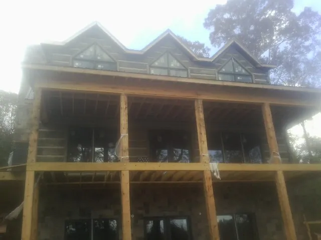 Dormers and porch framing on a large log home under construction — Roof Coating work by our crew in Jarrettsville