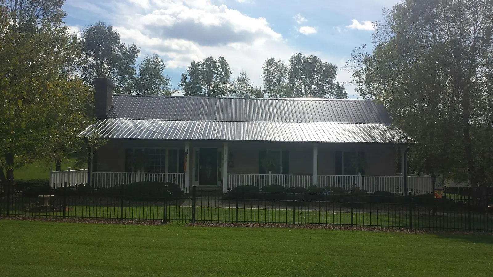 Gray metal roof on a brick ranch with a full width front porch — Gutter Guard Installation work by our crew in Jarrettsville