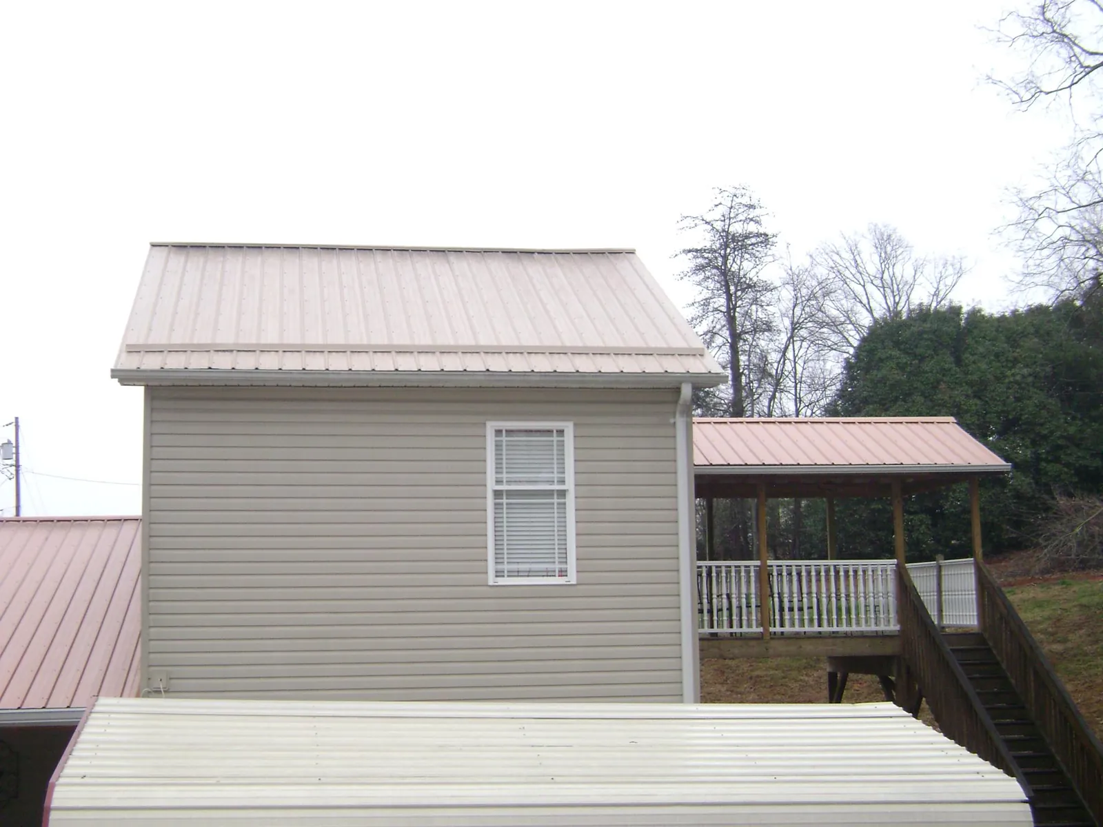 Tan metal roofs on a two story addition and attached porch, from a Roof Replacement job in Jarrettsville