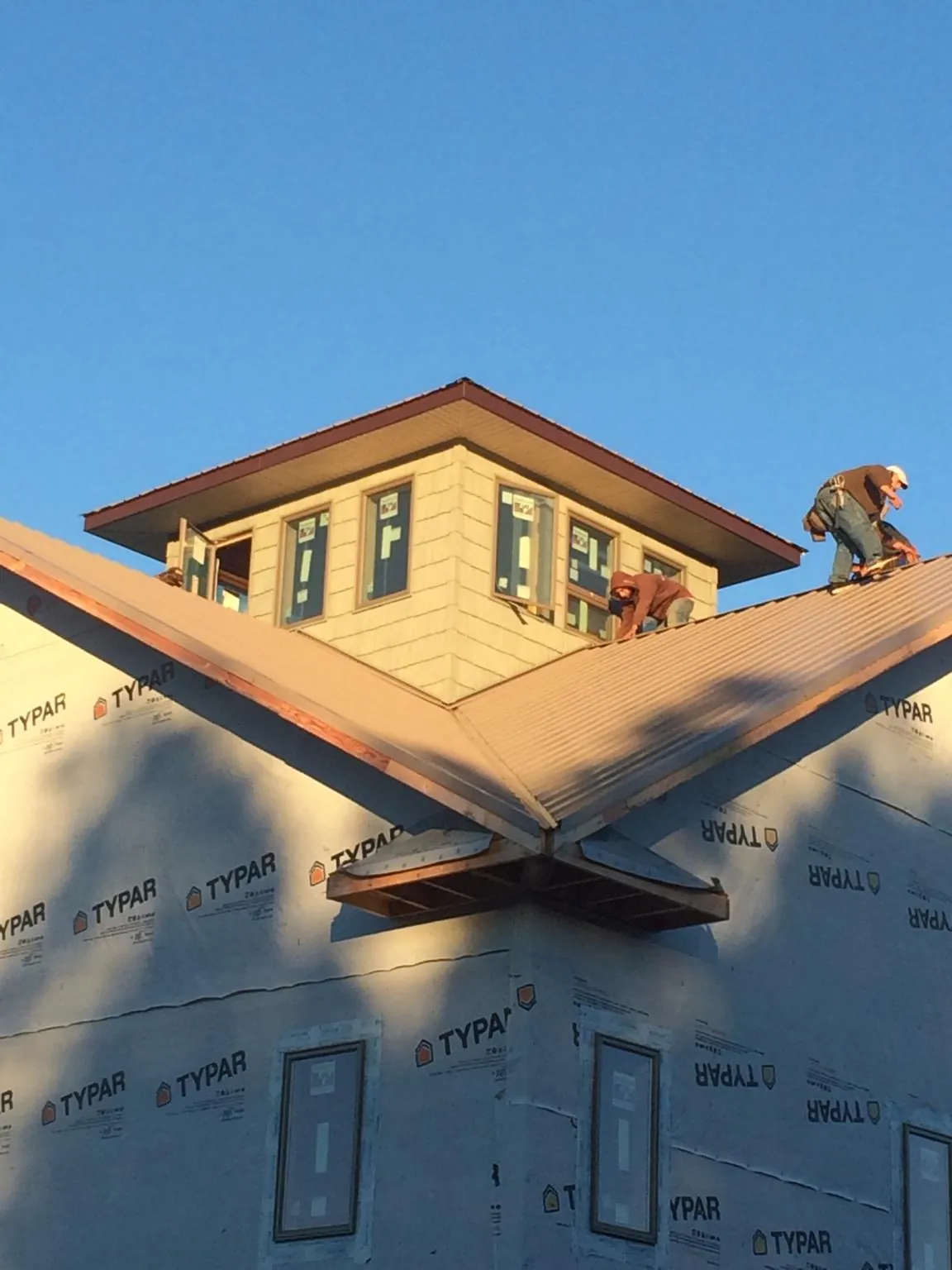 Roofers working around a rooftop cupola on a new metal roof at sunset — Roof Waterproofing in Jarrettsville by Roofing Brothers